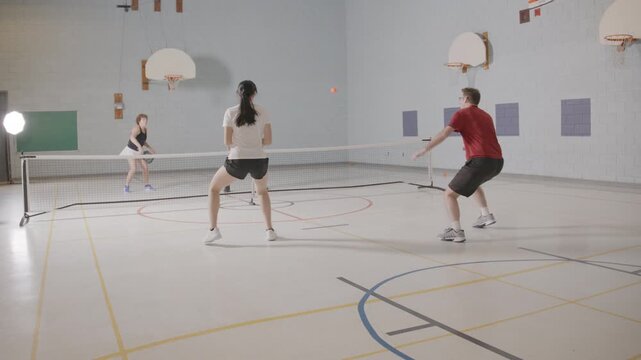 Co ed pickleball players in a modern gymnasium