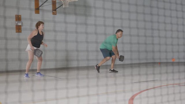 Co ed pickleball players in a modern gymnasium