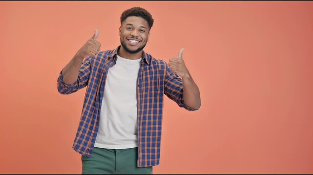 A person wearing a plaid shirt is making a thumbs up sign, a positive gesture