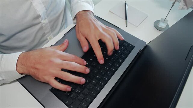 Man typing on laptop keyboard at office desk overhead view with documents and pen