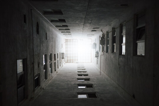 Upward view through narrow concrete lightwell of urban residential courtyard reveals repetitive windows, dramatic architectural geometry and limited daylight in enclosed building space.