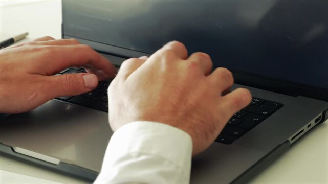 Businessman hands typing on laptop keyboard during corporate work in modern tech office