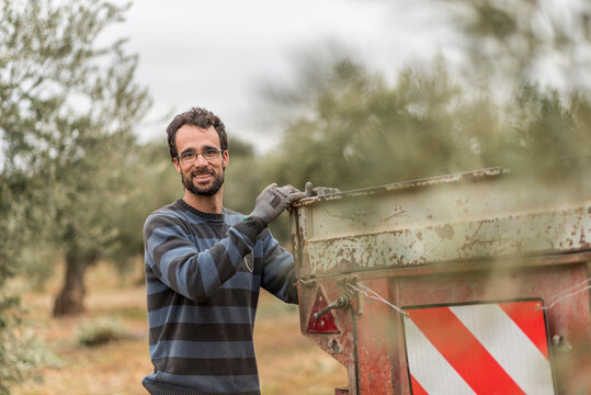 agricultural workers pose beside the trailer among olive trees