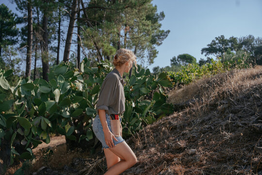 Female Gardener Walking Uphill Through Dry Mediterranean Garden with Cactus