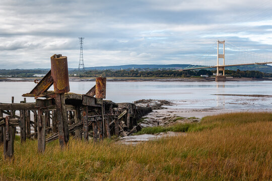Historic wooden remains of Aust Ferry Pier with Severn Bridge in background