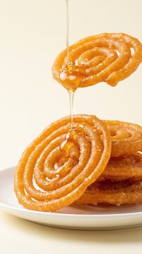Indian jalebi with sugar syrup dripping onto a plate, traditional Indian sweet, festive dessert, golden crispy spirals, glossy caramelized glaze, close up, tempting food texture