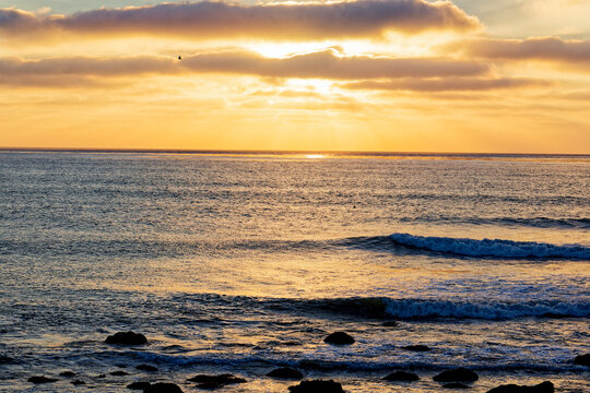 Golden Sunset Over Ocean Waves and Rocky Shore