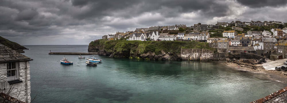 Panoramic view of Port Isaac harbour and coastal village under cloudy skies