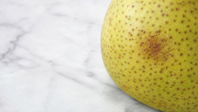 Pear skin speckled texture macro on white marble with copy space