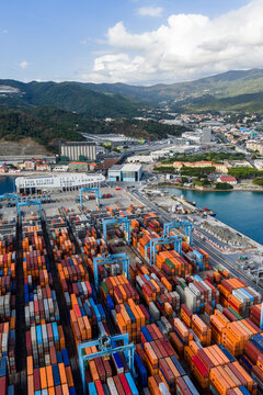 Aerial view of the busy container terminal with colorful shipping containers and gantry cranes at the port of Vado Ligure, Liguria, Italy.