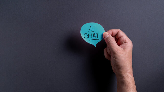 Hand holding speech bubble with AI chat message on black background during a discussion about artificial intelligence technology