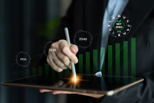 A business professional focuses on a tablet screen, using a stylus to analyze a digital graph showing sustainability goals and net zero initiatives by 2040. Gantry