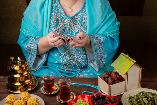A Muslim woman in a blue hijab is reciting zikr before iftar during Ramadan. Horizontal photo.