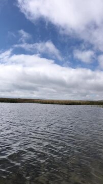 High Altitude Lake in Junin, Peru, with Rippling Water, Reed Beds, Andean Mountains and Cloudy Sky