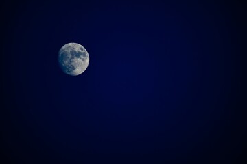 Waxing gibbous moon in a deep blue night sky with copy space © Tom