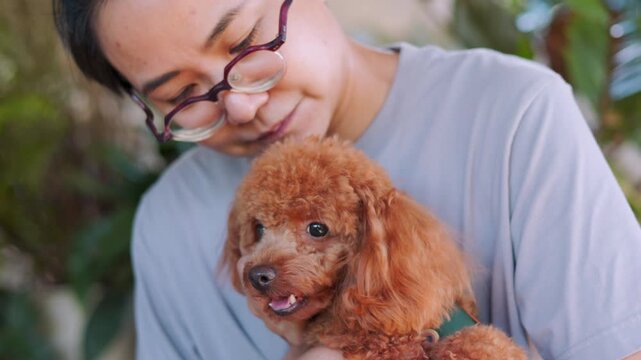 Asian girl affectionately hugging her adorable brown poodle. The close up framing beautifully highlights the dog's face and their strong connection with calm outdoor lifestyle atmosphere.