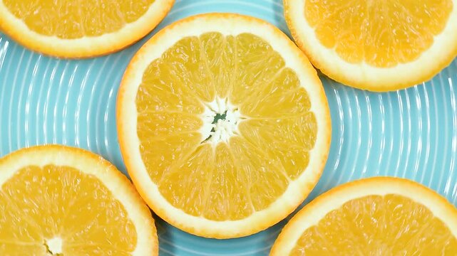 orange fruit slices on light a blue plate, extreme close-up, rotating video.