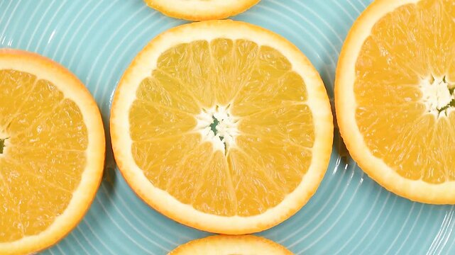 orange fruit slices on a light blue plate, extreme close-up, rotating video.