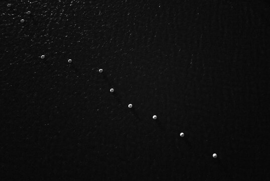Aerial view of a diagonal line of white navigation buoys floating on dark water in Ekenas, Uusimaa, Finland.
