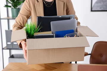 Obraz na płótnie Canvas Unemployed woman holding box with packed things in office, closeup