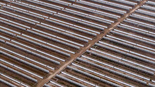 Aerial view of Central Termosolar Helioenergy 1 solar power plant with rows of parabolic trough mirrors in the arid landscape of Ecija, Andalusia, Spain.