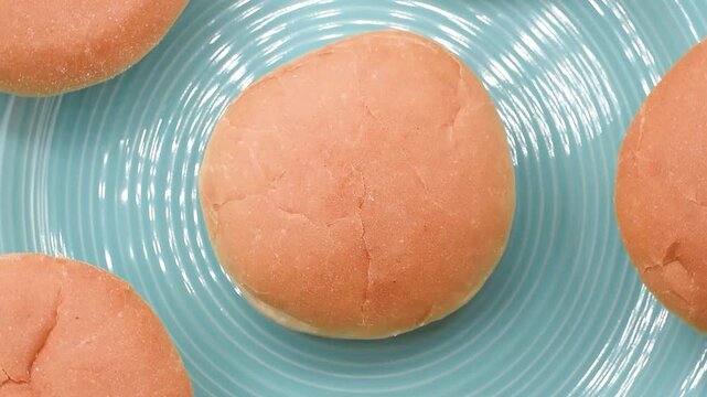 Italian soft round bread buns on a blue plate, extreme close-up, rotating video.