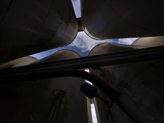 Netherlands - 10 september 2026, Den Bosch: Skyward View Between Tall Metal Industrial Silos © MyStockVideo