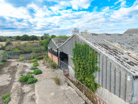 Drone view of a now derelict dairy farm in Essex, UK. Showing the asbestos roof and overgrown hay storage areas. In the distance would have been the milking parlour.