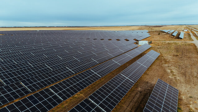 Aerial view of a large solar farm with rows of photovoltaic panels stretching across the rural landscape in Utrine, Vojvodina, Serbia.