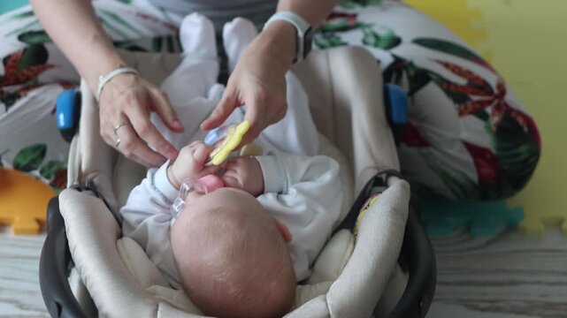 Mother playing with newborn baby in car seat