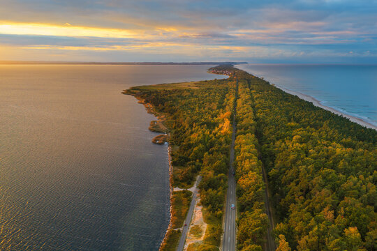 Aerial view of the Hel Peninsula at sunset, with a road through pine forests between the Baltic Sea and the Bay of Puck in Chalupy, Pomeranian Voivodeship, Poland.
