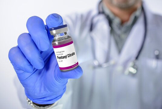 Doctor in medical uniform holding a glass vial of Fentanyl Citrate injection