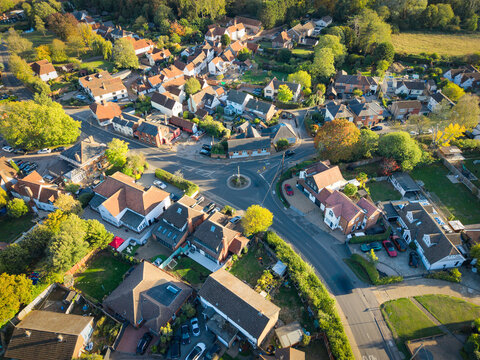 Detailed drone view of a typical village in rural Essex, UK. Showing the small roundabout near the centre of the image, surrounded by affluent private housing.