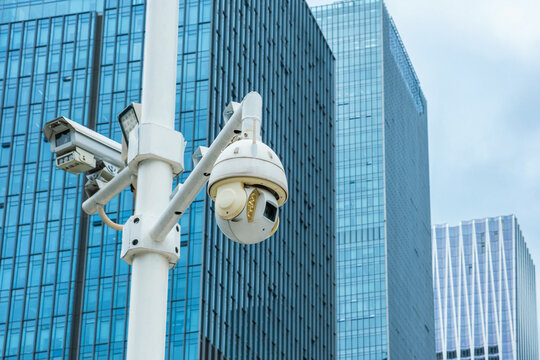 CCTV surveillance cameras on pole against modern office buildings in Shenzhen city, China. Urban security, video surveillance, public safety, smart city technology, security monitoring