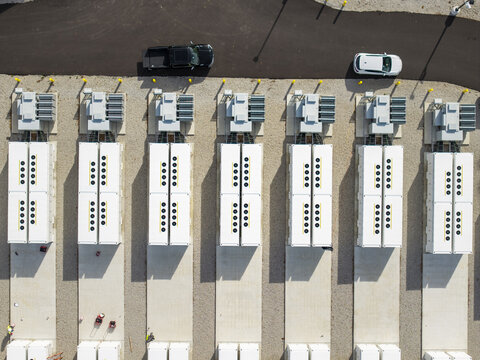 Aerial view of the Medway Grid Battery Energy Storage System featuring rows of white battery containers with cooling fans on a gravel site in Medway, Massachusetts, United States.