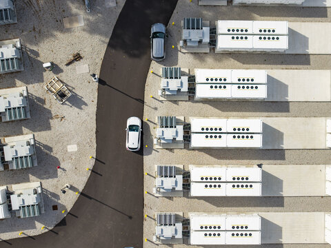 Aerial view of the Medway Grid Battery Energy Storage System with rows of white battery containers, transformers, and a paved access road in Medway, Massachusetts, United States.