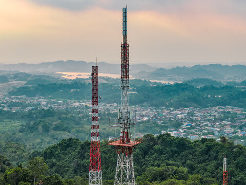 Aerial view of television broadcasting station towers rising above the lush green hills and urban landscape of Samarinda, East Kalimantan, Indonesia.