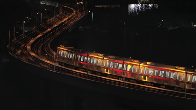 Elevated metro train making a complete turn on a curve at night