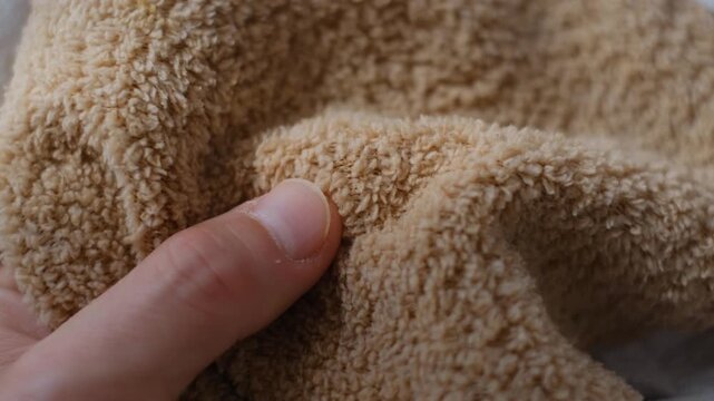 Close up macro shot of a hand touching soft beige microfiber fabric texture