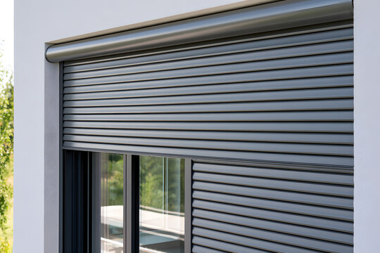 Close-up of a modern grey metal roller shutter on a house window. An automatic external blind provides home security and privacy for a residential building. A protective aluminum shutter system covers