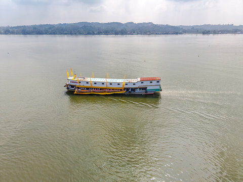 Tenggarong, Indonesia - 27 September 2026: Aerial view of the Ngulur Naga Erau boat carrying people on the Mahakam River, with traditional yellow decorations and a calm water surface.
