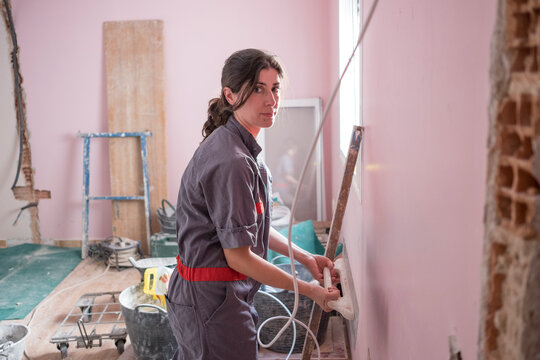 woman working at home with mansonry and renovation, Uniforming the wall paste with the flat tool