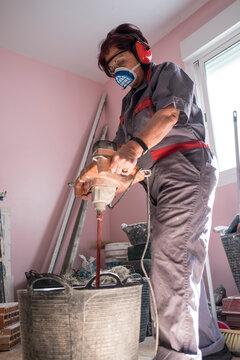 mature woman bricklayer mixes the cement mass in the remodeling of the room of a house