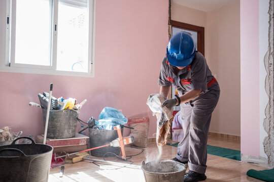 mature woman bricklayer prepares the mixture of cement and plaster mass in the remodeling of the room of a house