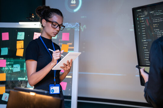 Software developer writing on digital tablet during training code at meeting in data center