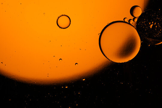 Macro view of orange bubbles floating in liquid oil mixture