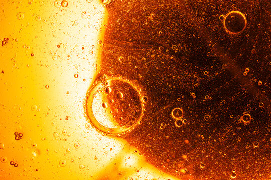Golden bubbles floating within clear yellow oil texture