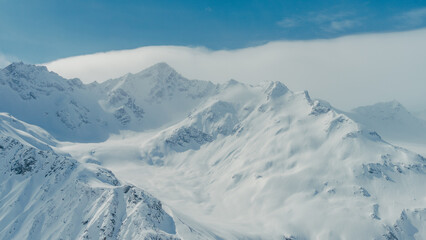 Snow-covered Mount Elbrus ridges and summits in Caucasus Mountains aerial panorama under blue sky © ossyffer