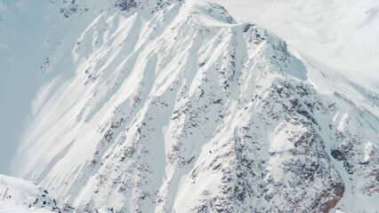 Mount Elbrus snow-covered steep slopes with rocky outcrops and wind-sculpted cornices in Caucasus Mountains © ossyffer