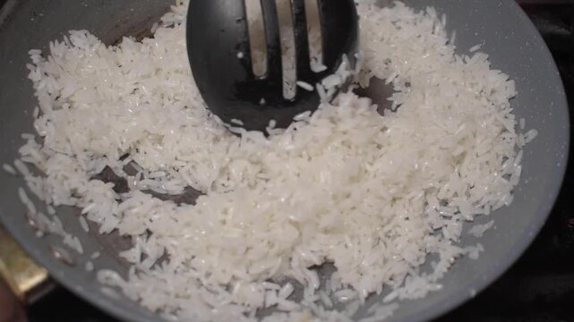 Cuchar&oacute;n negro revolviendo arroz para freirlo o prepararlo 